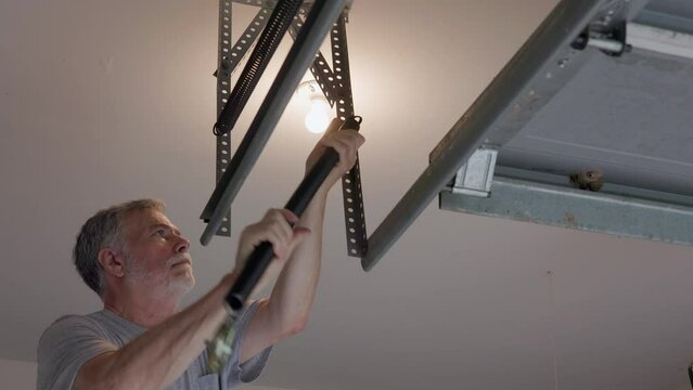 A homeowner or handyman type installing a new heavy duty spring on the garage door automatic opener.