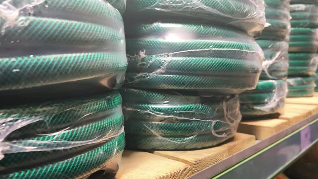 New coiled garden hoses lie on the shelves of a hardware store or garden supply shop