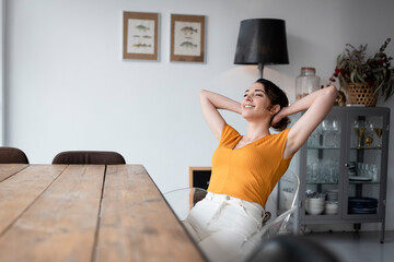 Woman sitting at dining table at home relaxing