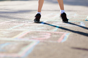 Kids play hopscotch in summer park. Outdoor game.