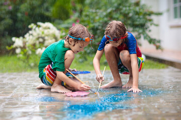 Fototapeta na wymiar Kids playing in the rain. Chalk drawing fun.