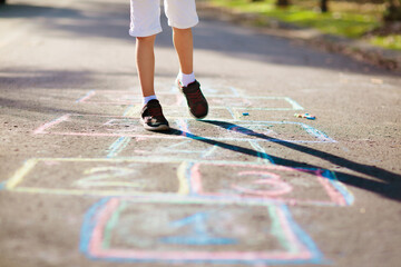 Kids play hopscotch in summer park. Outdoor game.