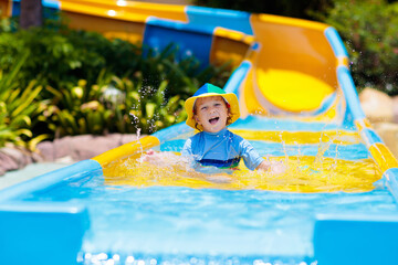 Kids on water slide in aqua park. Summer vacation