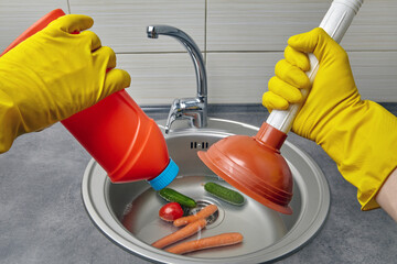 Hands in yellow rubber gloves hold a plunger and pipe cleaner