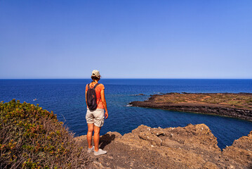 Woman looking the sea from the top of the volcano called Monte Nero, Linosa. Sicily