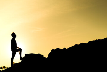 silhouette of a man climbing a mountain, triumph and personal achievement, concept of freedom