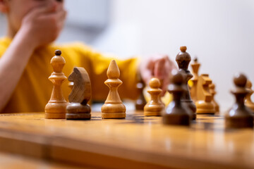 Brunette boy playing a game of chess on large chess board at home. selective focus. 