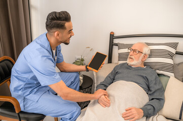 General practitioner examining a bedridden man during the home visit