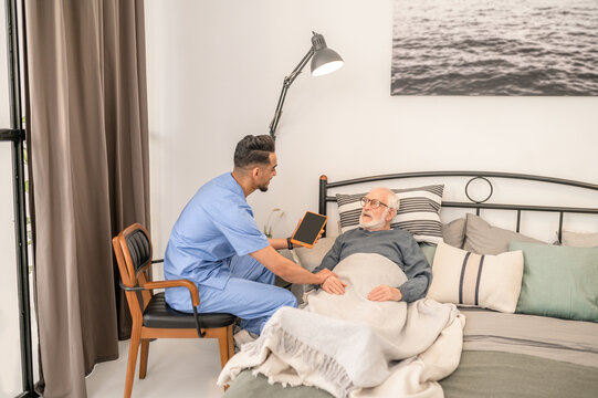 Doctor checking the health condition of a bedridden aged man