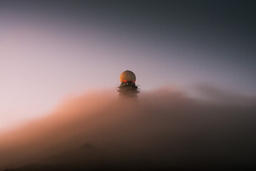 Low angle shot of a radar tower with dense clouds