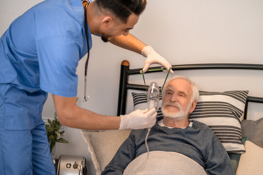 Nurse preparing an aged man for oxygenation