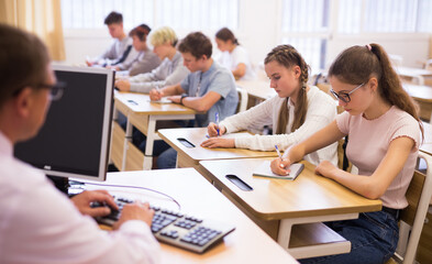 Group of focused teenage students sitting at classroom working at class