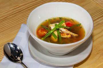 Chicken soup with vegetables in white bowl. Grey stone background.