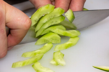 The chef cuts cucumber on a light background. A concept of losing healthy and wholesome food, detox, vegetatry, diet, cooking. Slow food, comfort food, healthy diet, clean eating.