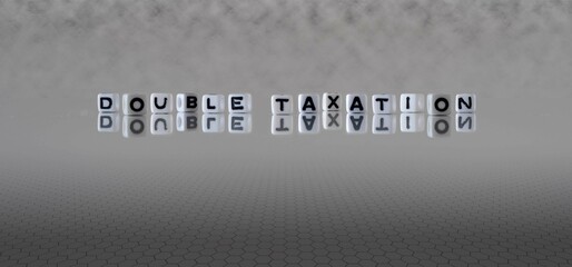 double taxation word or concept represented by black and white letter cubes on a grey horizon background stretching to infinity