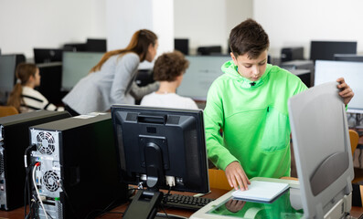 Focused tween schoolboy using copier to make copy of lecture note in college computer class. Modern technologies in teaching children ..