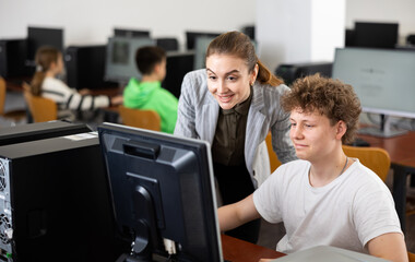 Fototapeta na wymiar Positive female teacher tells a teenager how to work on a computer
