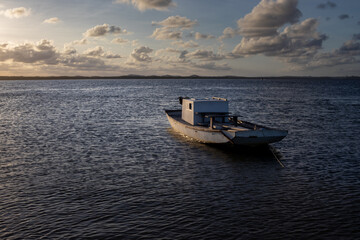 Fototapeta na wymiar transport boat floating stopped over river illuminated by sunset light.