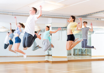 Fototapeta na wymiar Group of cheerful teenagers dancing and jumping in dance studio during class, side view