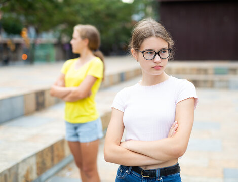 Two teenager girls feeling sad because quarreling in urban park.