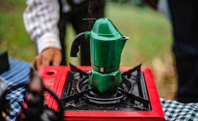 Make an espresso using the green moka pot on the red picnic gas stove.