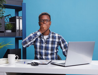 Young adult agency worker doing three wise monkeys gesture to desk while in office workspace. Business man doing philosophical proverbial wise gesture with hands. Speak no evil concept.