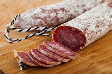 Traditional Catalan dry cured pork sausage Longaniza with sliced pieces on wooden board..