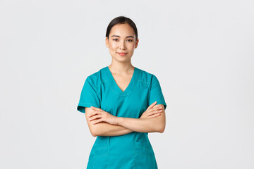 Covid-19, healthcare workers, pandemic concept. Confident smiling asian nurse in scrubs standing...