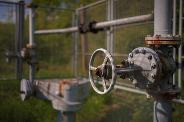 View of the gas facility secured in a rural location. Rusted valves and pipes.