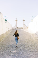 A young 20s woman running up a cobble stone pathway in Portugal, Europe. 