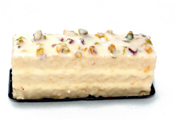 white vanilla cake gateau piece covered with nuts and stuffed with whipping cream isolated on white...