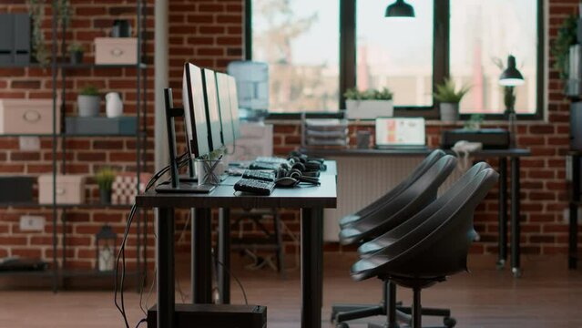 Nobody in office used for call center telecommunication, giving support to helpline clients with headsets and monitors. No people at customer service workstation with modern devices.