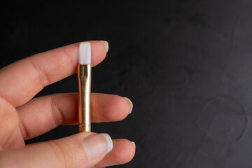 detalle de pincel en mano, mostrando la punta de cerda sintética suave, sobre fondo negro
