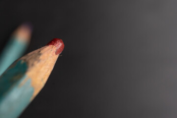 close up de punta de lápiz de color rojo carmín desgastada sobre fondo negro de madera
