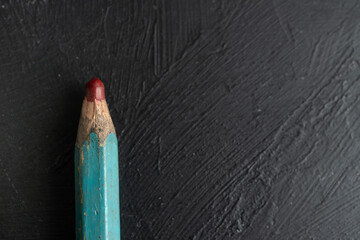 close up de punta de lápiz de color rojo carmín desgastada sobre fondo negro de madera
