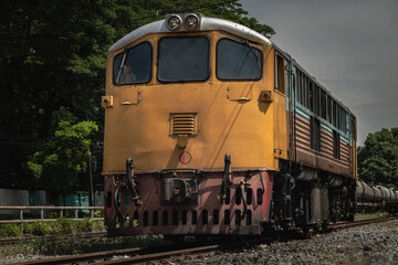 Front view of The diesel electric locomotive is parked on Old railroad tracks. The empty passenger yellow train, Selective focus.