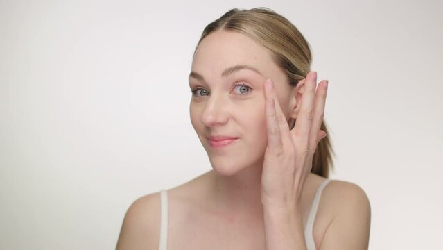 Beautiful young woman dabs anti aging cream lotion to neck and face