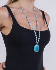 Vertical shot of a female wearing a precious blue crystal necklace against a gray background
