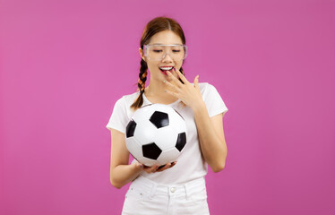 Asian Young woman in white t-shirt over isolated pink background holding a soccer ball, football concept