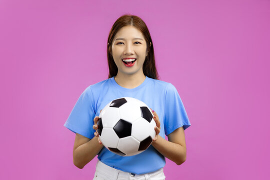Happy Young Asian woman isolated pink background looking at camera, holding a soccer ball, FIFA World Cup concept