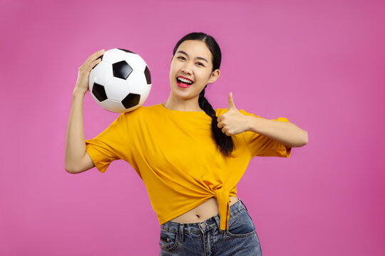 Asian Young woman over isolated pink background holding a soccer ball, sport concept
