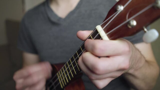 Close up of the neck and headstock as a pan strums a soprano ukulele.