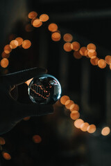 Hand of a woman holding a crystal ball on bokeh lights background