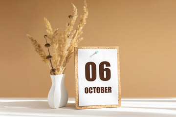 october 6. 6th day of month, calendar date.White vase with dried flowers on desktop in rays of sunlight on white-beige background. Concept of day of year, time planner, autumn month