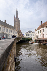 Fototapeta na wymiar Moored tour boat next to a vine covered bridge in the heart of Brugge Belgium