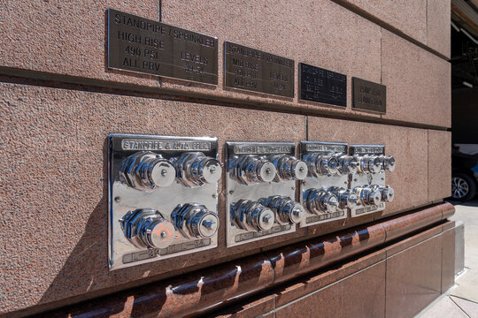 Fire Department Connections for Sprinkler Systems and pump test connections on the exterior wall of a high rise building. 
