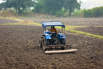 Indian farmer working with tractor in agriculture field