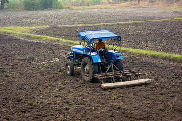 Indian farmer working with tractor in agriculture field