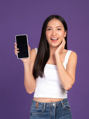Fototapeta premium Beautiful Asian brunette woman cute girl in white tank top ,Excited surprised girl showing smart phone with blank screen , black screen isolated purple background , Mock Up Image