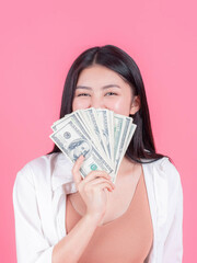 Successful beautiful Asian business young woman holding money US dollar bills in hand on pink background , business concept